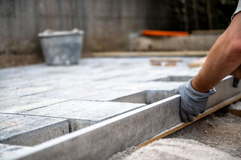 Fotografia de un trabajador de obra aplicando un tratamiento antideslizamiento en una superficie en construcción.