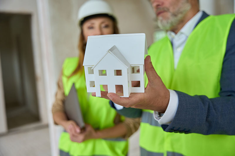 Foto on es veu un home ensenyant una maqueta d'una casa a la responsable de reformes d'habitatges.